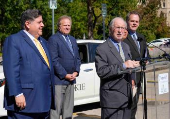 Pictured, from left, at a ceremony to hand over the EV rebate are Illinois Governor JB Pritzker;  Illinois Commerce Commission Chairman Doug P. Scott; Village of Skokie Mayor George Van Dusen (at podium); ComEd President and CEO Gil C. Quiniones; and City of Geneva Mayor and Metropolitan Mayors Caucus Executive Board Chairman Kevin R. Burns. Photo: Rich Cahan