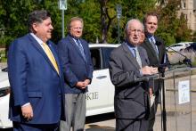 Pictured, from left, at a ceremony to hand over the EV rebate are Illinois Governor JB Pritzker;  Illinois Commerce Commission Chairman Doug P. Scott; Village of Skokie Mayor George Van Dusen (at podium); ComEd President and CEO Gil C. Quiniones; and City of Geneva Mayor and Metropolitan Mayors Caucus Executive Board Chairman Kevin R. Burns. Photo: Rich Cahan